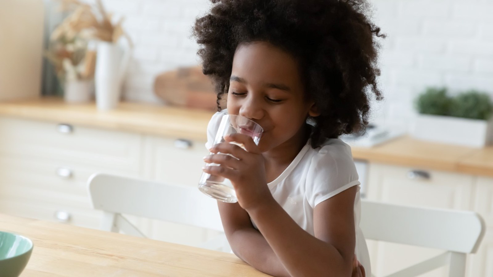 Child drinking a glass of water at home